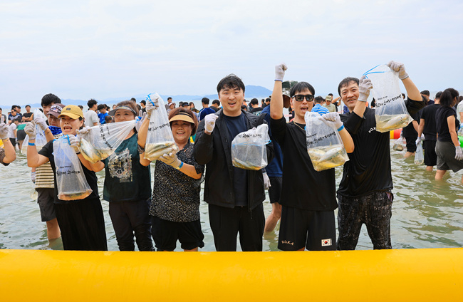 1-1. 관광객들이 직접 작은 전어를 들고 환한 미소를 짓고 있다..jpg